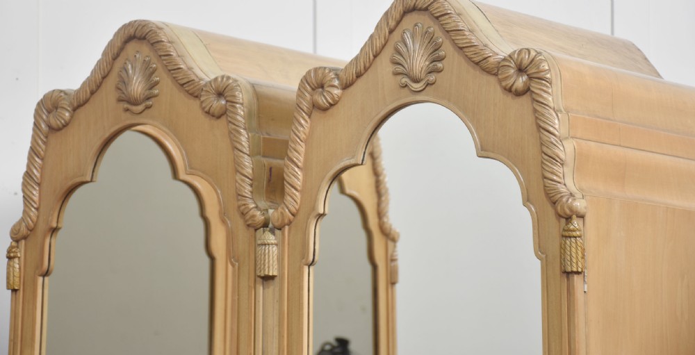 A near pair of tall light walnut wardrobes featuring twin arched mirrored doors, rope-twist carved borders, shell motifs, and two base drawers on carved feet. View VIII