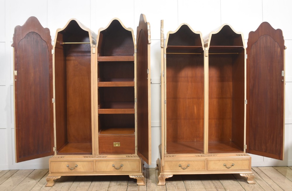 A near pair of tall light walnut wardrobes featuring twin arched mirrored doors, rope-twist carved borders, shell motifs, and two base drawers on carved feet. View IX