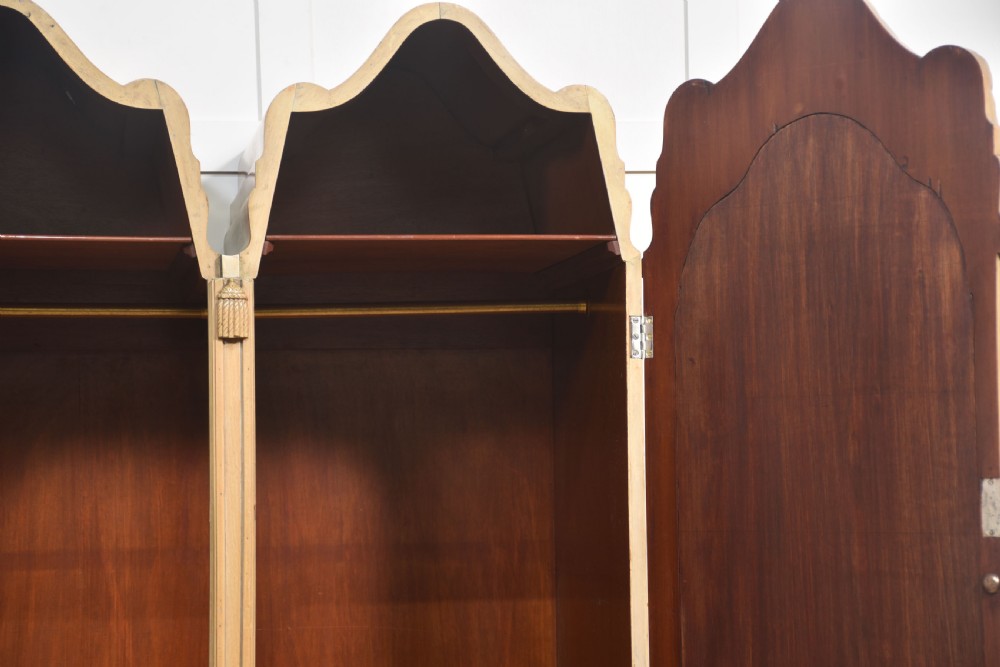 A near pair of tall light walnut wardrobes featuring twin arched mirrored doors, rope-twist carved borders, shell motifs, and two base drawers on carved feet. View XIII