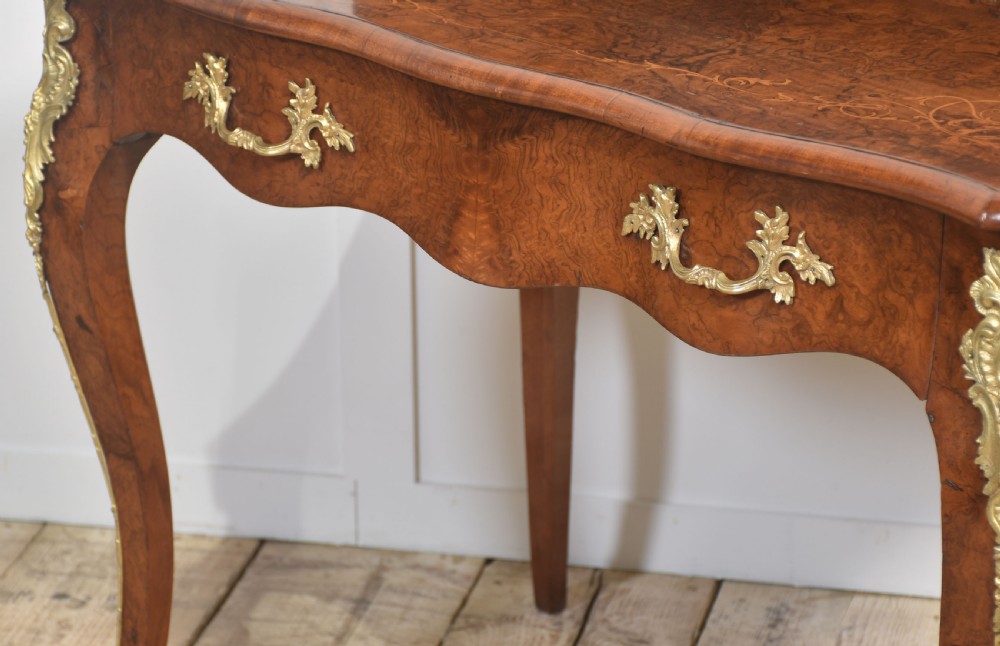 A 19th-century French writing desk crafted from figured walnut wood featuring gilt-bronze ormolu mounts, cabriole legs, floral marquetry drawer fronts, and an upper superstructure with pigeonholes. View X