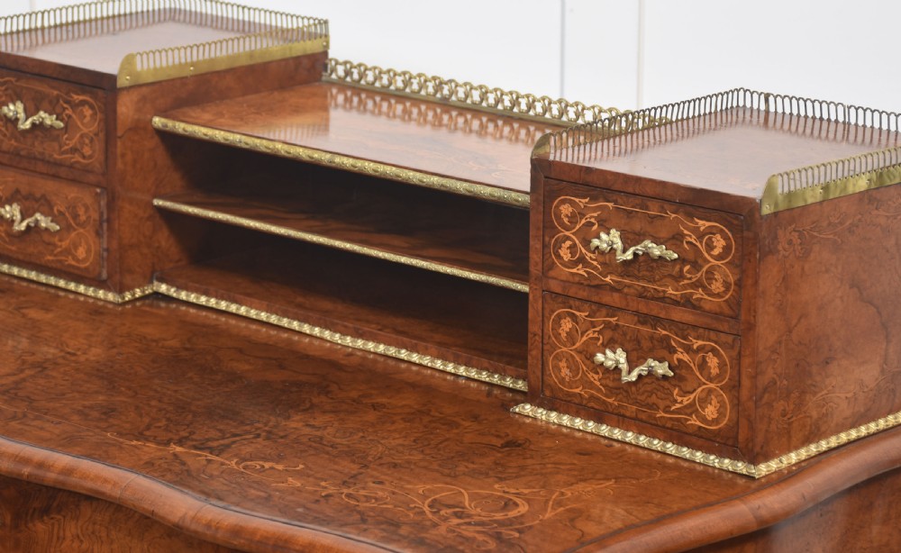 A 19th-century French writing desk crafted from figured walnut wood featuring gilt-bronze ormolu mounts, cabriole legs, floral marquetry drawer fronts, and an upper superstructure with pigeonholes. View XI