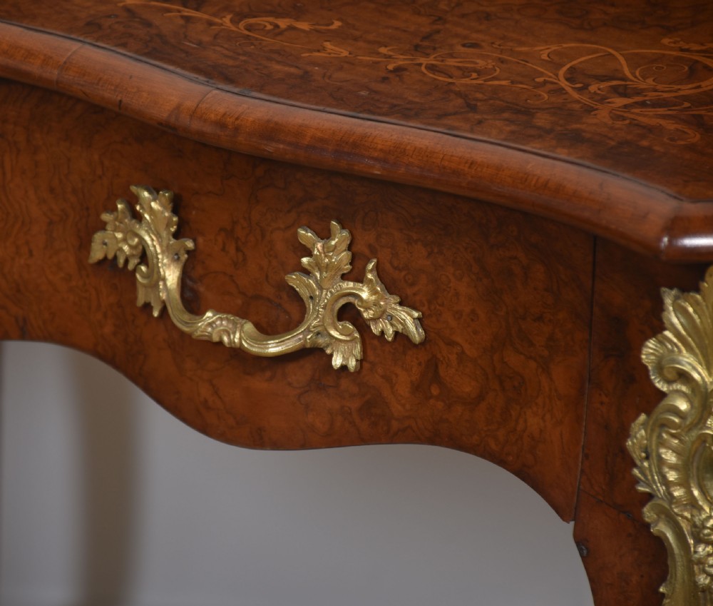 A 19th-century French writing desk crafted from figured walnut wood featuring gilt-bronze ormolu mounts, cabriole legs, floral marquetry drawer fronts, and an upper superstructure with pigeonholes. View XIII