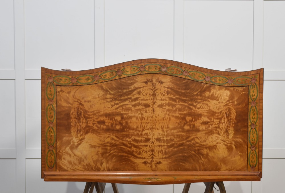 An antique painted satinwood dressing table featuring floral artwork, a central kneehole, side cupboards, drawers, brass handles, and a low gallery back. View XVI
