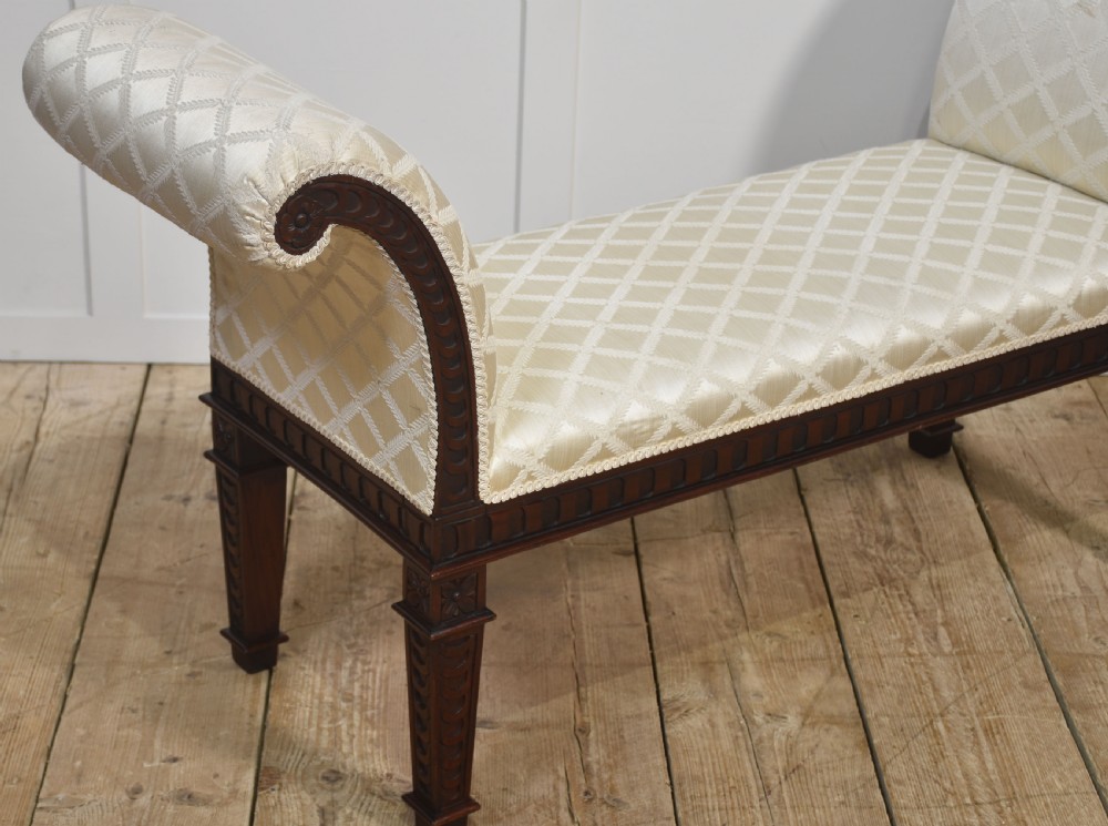 A carved mahogany window seat with out-curved scrolled arms, cream diamond-patterned fabric upholstery, and square tapered legs. View III