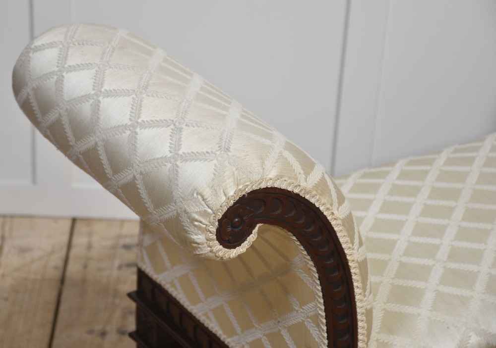A carved mahogany window seat with out-curved scrolled arms, cream diamond-patterned fabric upholstery, and square tapered legs. View V