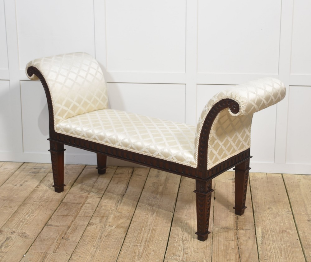 A carved mahogany window seat with out-curved scrolled arms, cream diamond-patterned fabric upholstery, and square tapered legs. View VIII