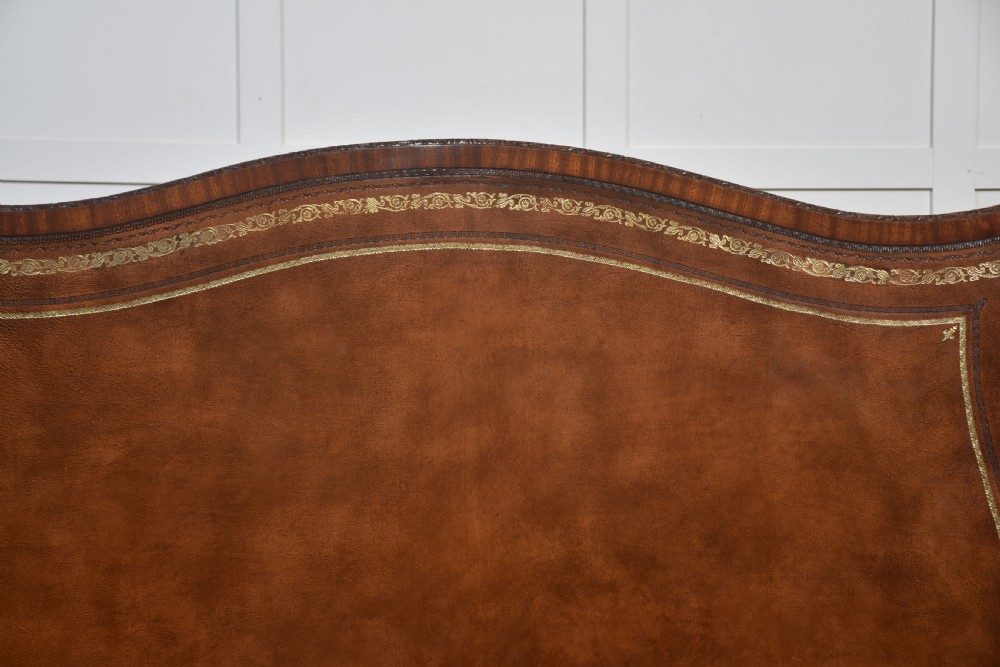 A large Chippendale Revival mahogany partners desk with a serpentine front, gilded leather inset writing top, and brass swan-neck handles. View XXII
