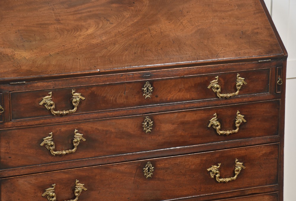 A George III mahogany bureau featuring a sloping fall-front lid above four graduated drawers with brass handles and bracket feet. View VIII