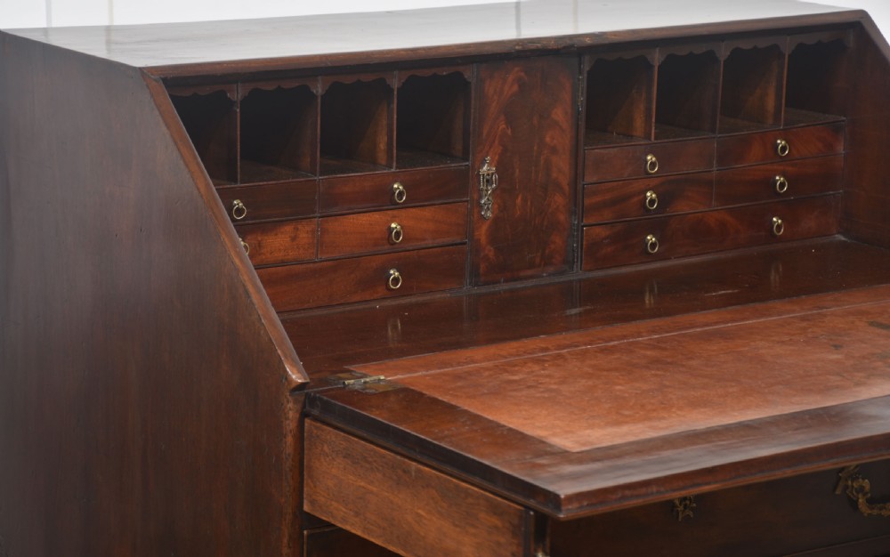 A George III mahogany bureau featuring a sloping fall-front lid above four graduated drawers with brass handles and bracket feet. View XIII