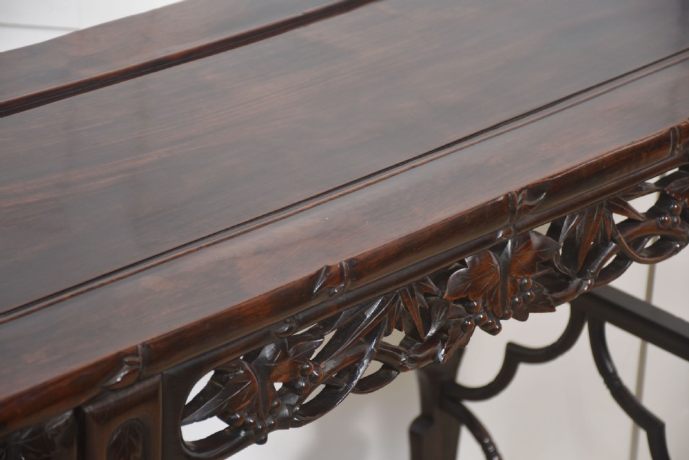 A dark hardwood Chinese altar table featuring openwork carved aprons, everted flanges, and decorative carved stretchers. View V
