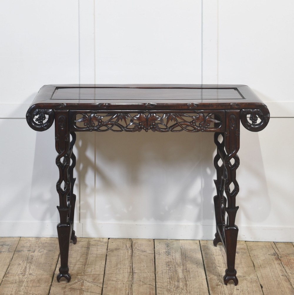A dark hardwood Chinese altar table featuring openwork carved aprons, everted flanges, and decorative carved stretchers. View VI