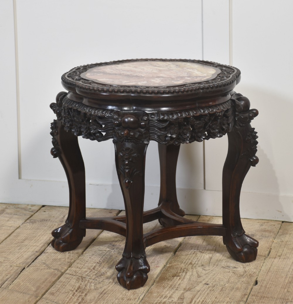 A circular dark rosewood side table featuring an inset pinkish marble top, openwork carved floral apron, cabriole legs, and an X-stretcher. View VIII