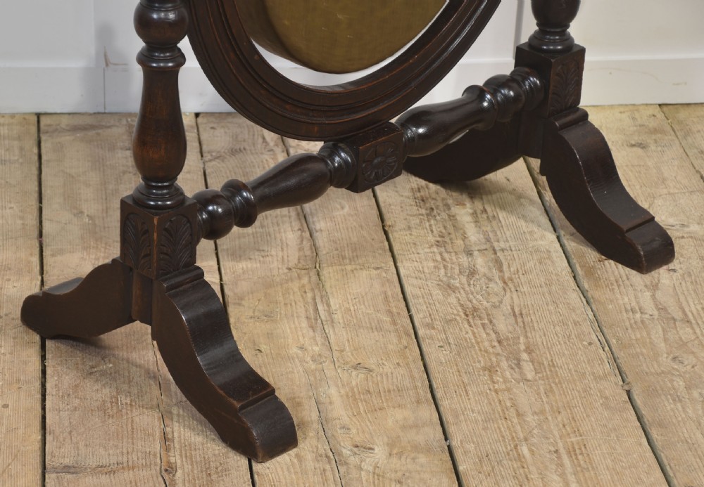 A freestanding dark oak frame with carved posts, turned finials, and shoe feet, housing a suspended circular brass gong with a matching beater attached at the side. View VII
