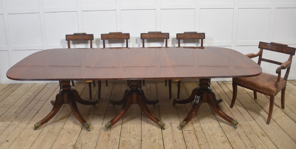 A long polished mahogany triple pedestal dining table featuring rounded corners, reeded splayed legs, and brass claw feet. View II