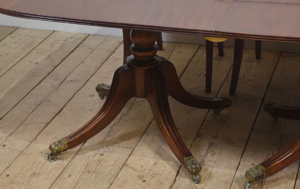 A long polished mahogany triple pedestal dining table featuring rounded corners, reeded splayed legs, and brass claw feet. View III
