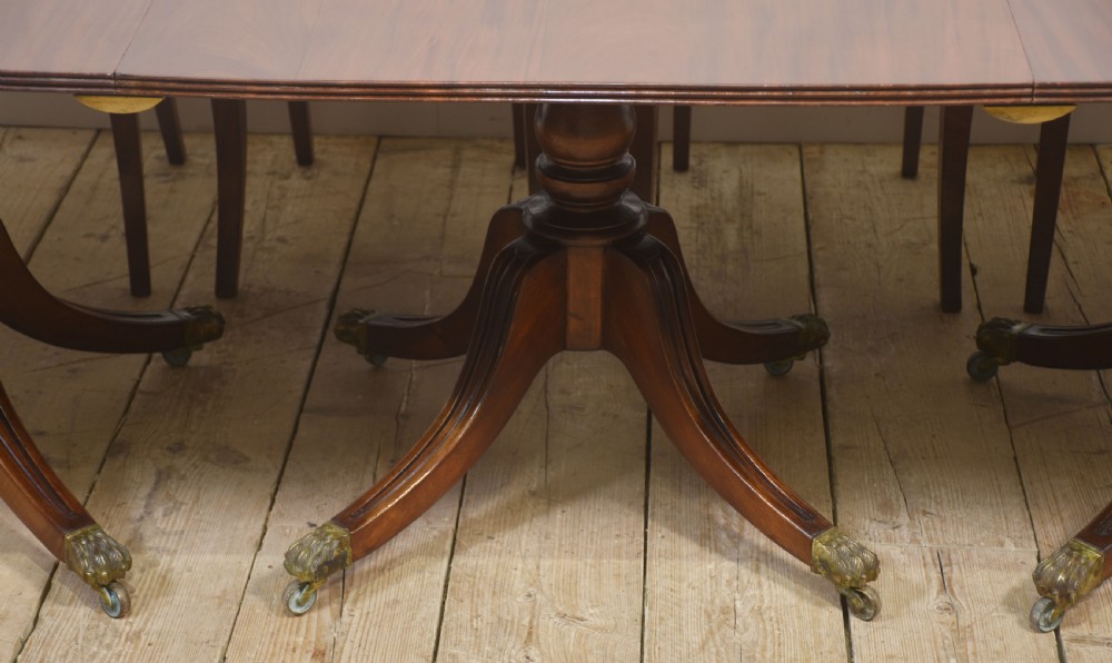 A long polished mahogany triple pedestal dining table featuring rounded corners, reeded splayed legs, and brass claw feet. View V