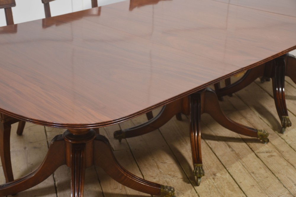 A long polished mahogany triple pedestal dining table featuring rounded corners, reeded splayed legs, and brass claw feet. View VI