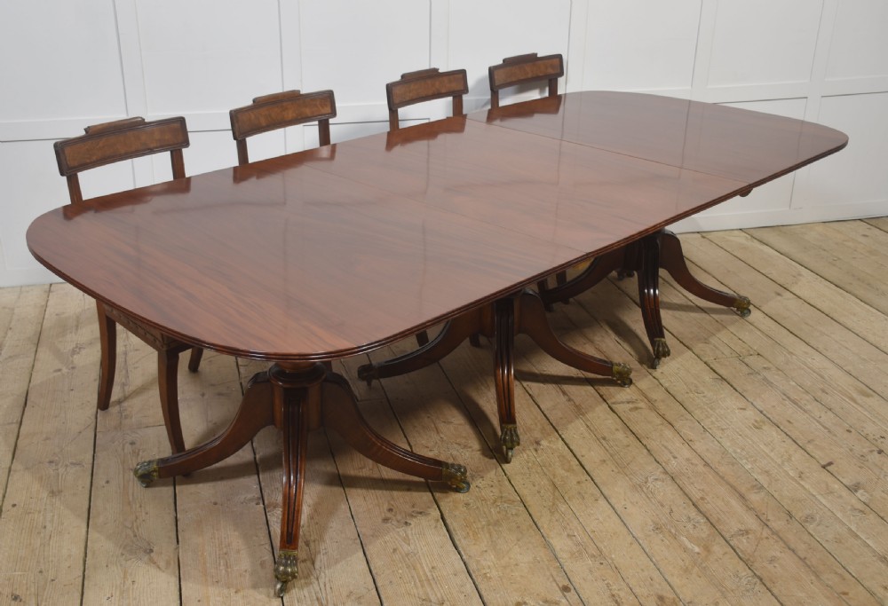 A long polished mahogany triple pedestal dining table featuring rounded corners, reeded splayed legs, and brass claw feet. View VII