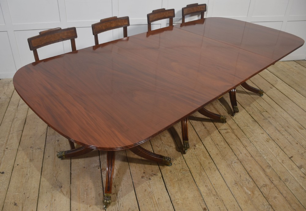 A long polished mahogany triple pedestal dining table featuring rounded corners, reeded splayed legs, and brass claw feet. View VIII