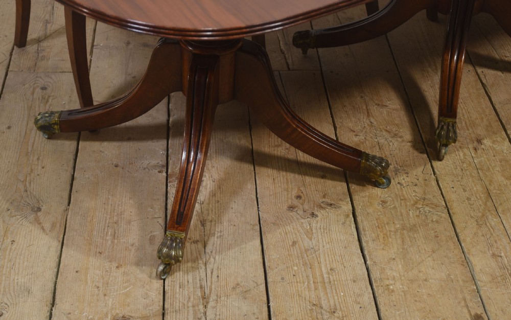 A long polished mahogany triple pedestal dining table featuring rounded corners, reeded splayed legs, and brass claw feet. View X
