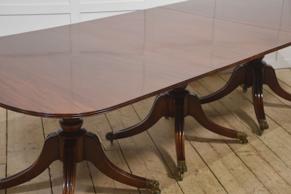 A long polished mahogany triple pedestal dining table featuring rounded corners, reeded splayed legs, and brass claw feet. View XII