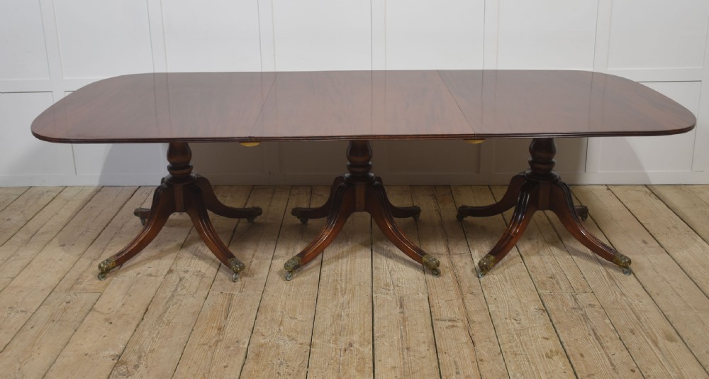 A long polished mahogany triple pedestal dining table featuring rounded corners, reeded splayed legs, and brass claw feet. View XIII