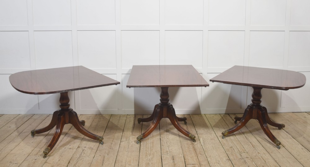 A long polished mahogany triple pedestal dining table featuring rounded corners, reeded splayed legs, and brass claw feet. View XIV
