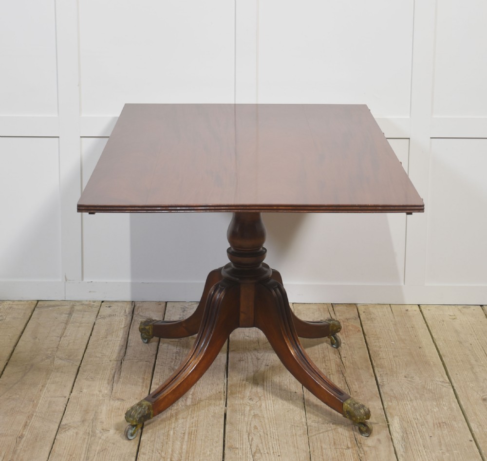 A long polished mahogany triple pedestal dining table featuring rounded corners, reeded splayed legs, and brass claw feet. View XV