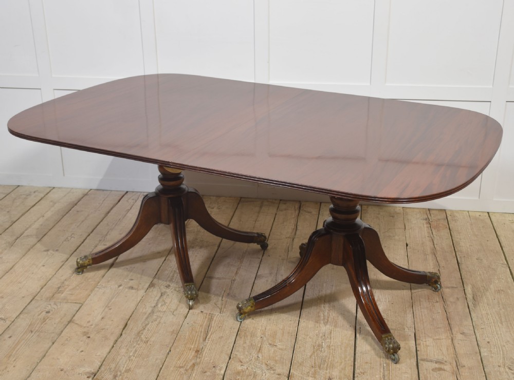 A long polished mahogany triple pedestal dining table featuring rounded corners, reeded splayed legs, and brass claw feet. View XVI
