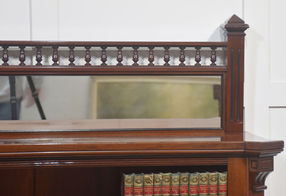 A Victorian mahogany open bookcase featuring four open shelves, fluted side columns, and a upper mirrored back with a turned spindle gallery. View II