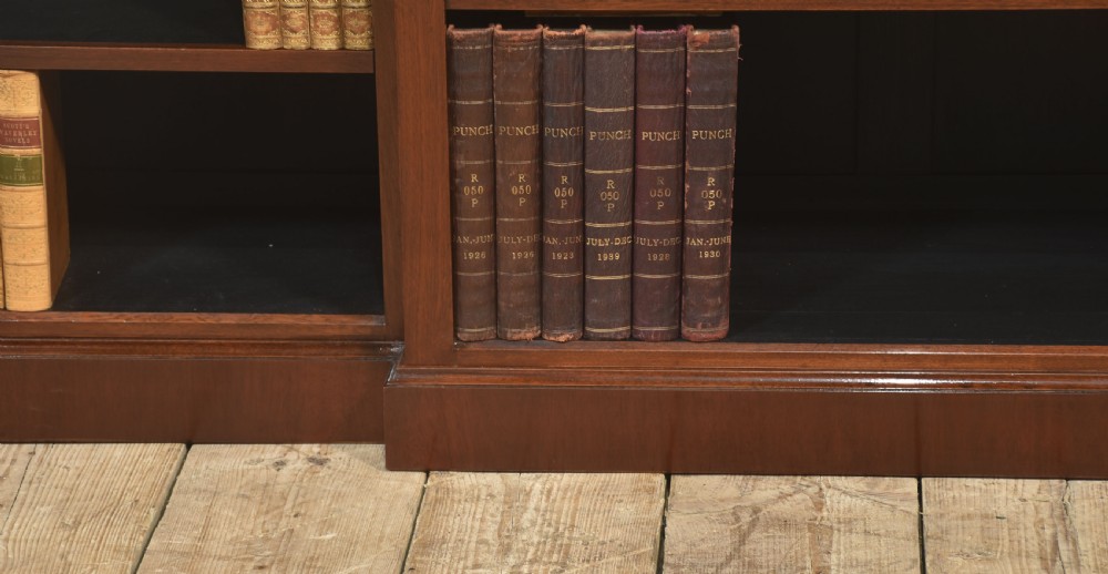 A wide mahogany open breakfront bookcase with four tiers of shelving containing antique leather-bound books. View II