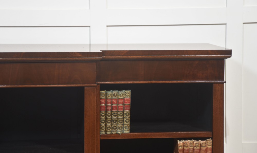 A wide mahogany open breakfront bookcase with four tiers of shelving containing antique leather-bound books. View III
