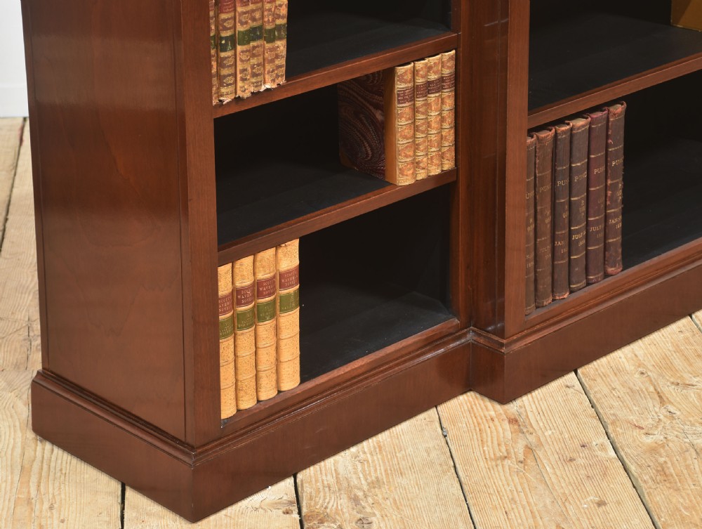 A wide mahogany open breakfront bookcase with four tiers of shelving containing antique leather-bound books. View VI