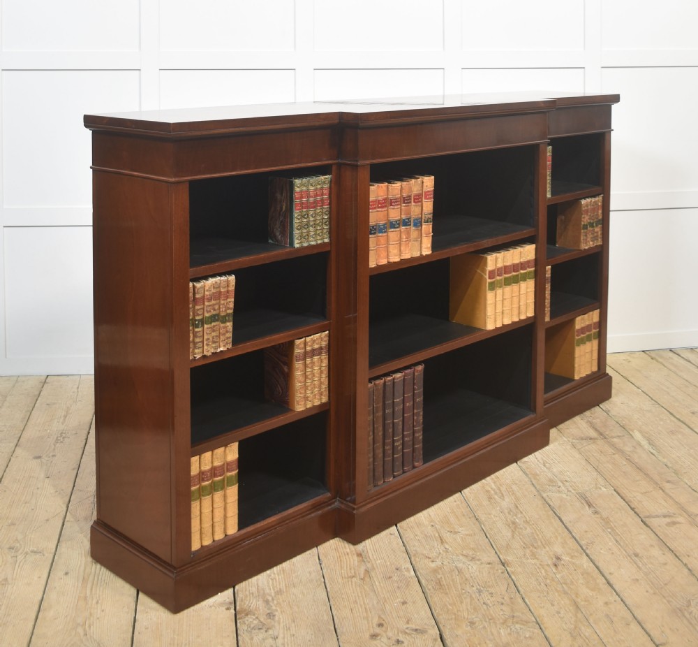A wide mahogany open breakfront bookcase with four tiers of shelving containing antique leather-bound books. View VII