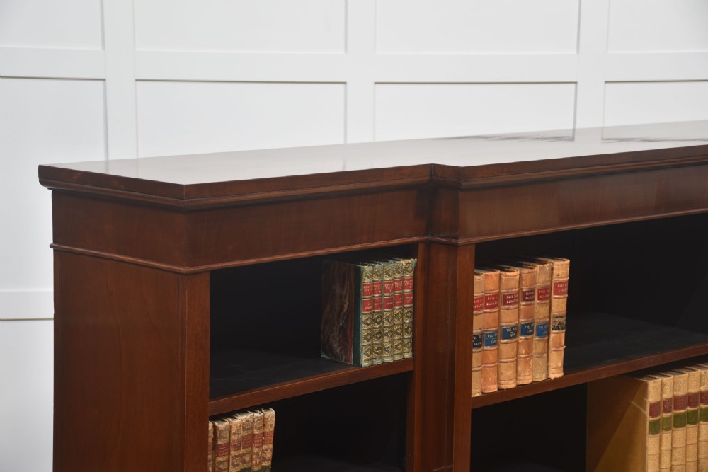 A wide mahogany open breakfront bookcase with four tiers of shelving containing antique leather-bound books. View VIII
