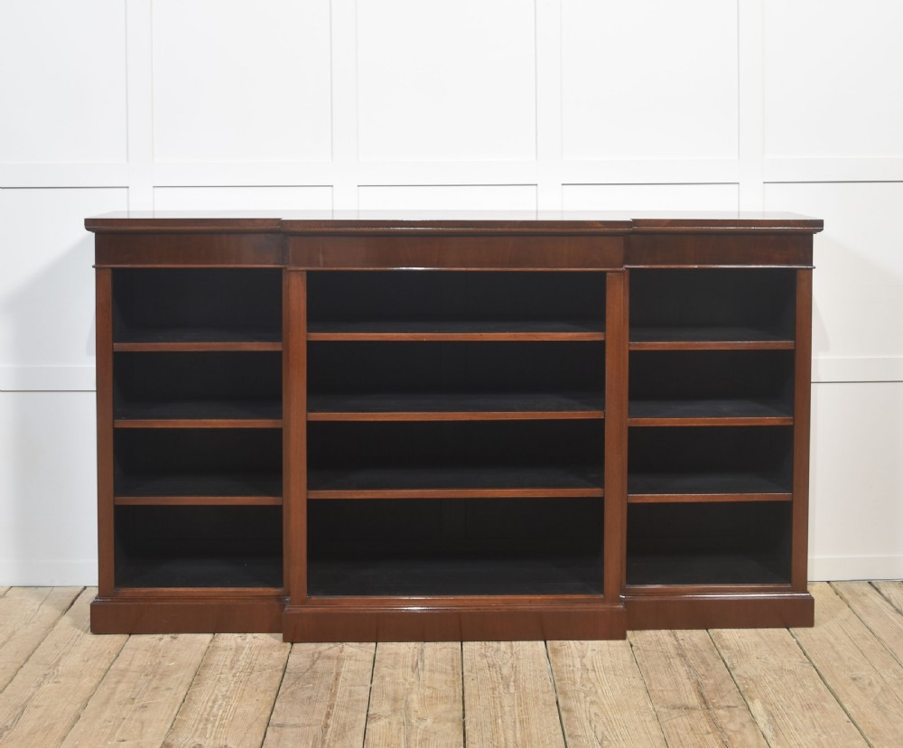 A wide mahogany open breakfront bookcase with four tiers of shelving containing antique leather-bound books. View IX