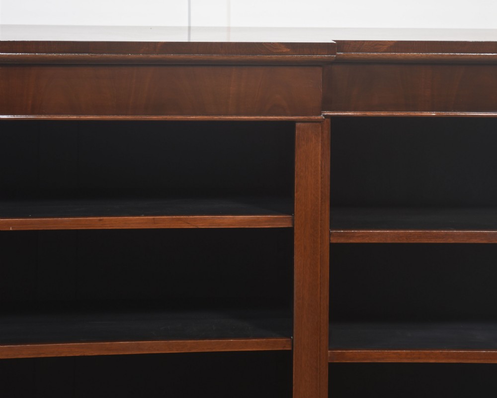 A wide mahogany open breakfront bookcase with four tiers of shelving containing antique leather-bound books. View X