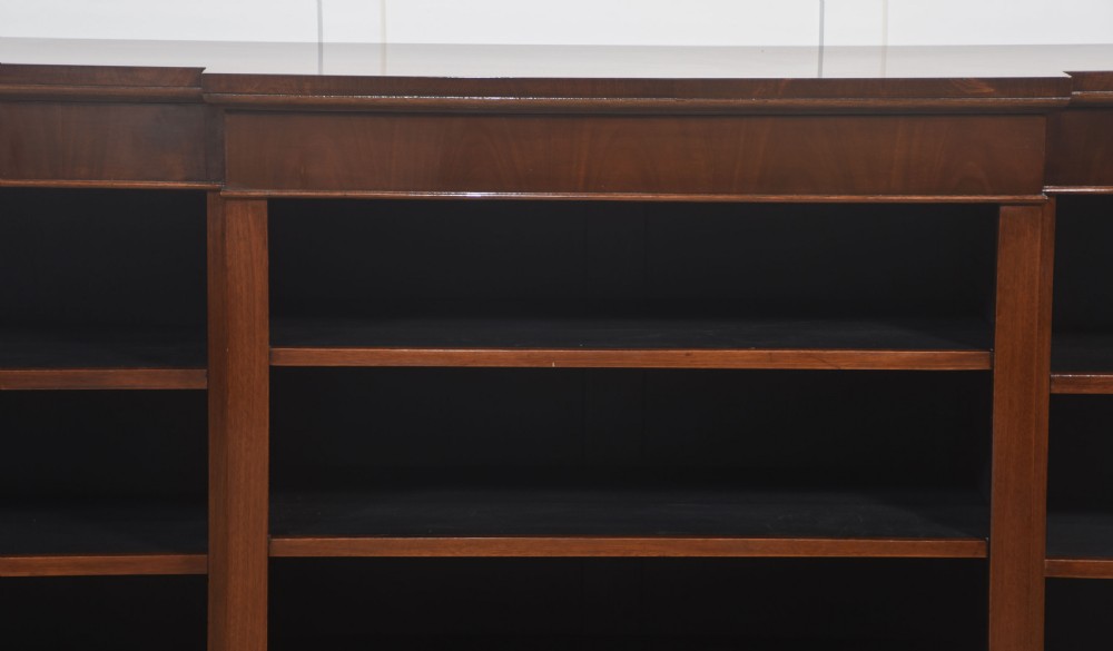 A wide mahogany open breakfront bookcase with four tiers of shelving containing antique leather-bound books. View XII