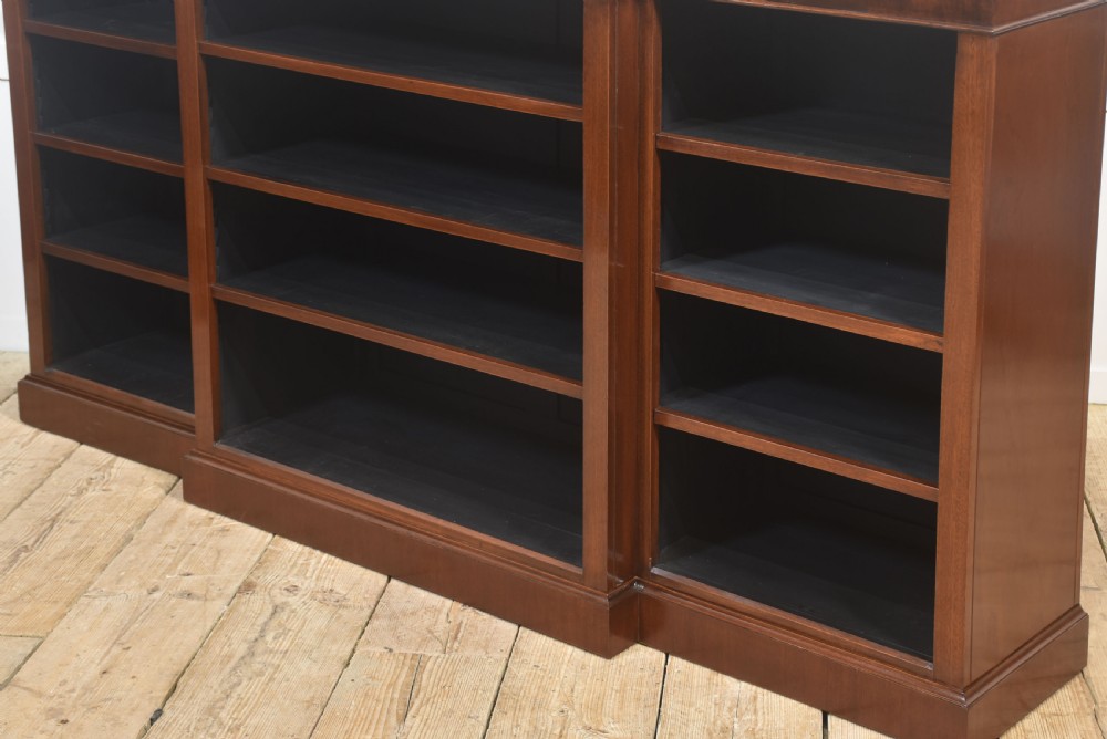 A wide mahogany open breakfront bookcase with four tiers of shelving containing antique leather-bound books. View XIV