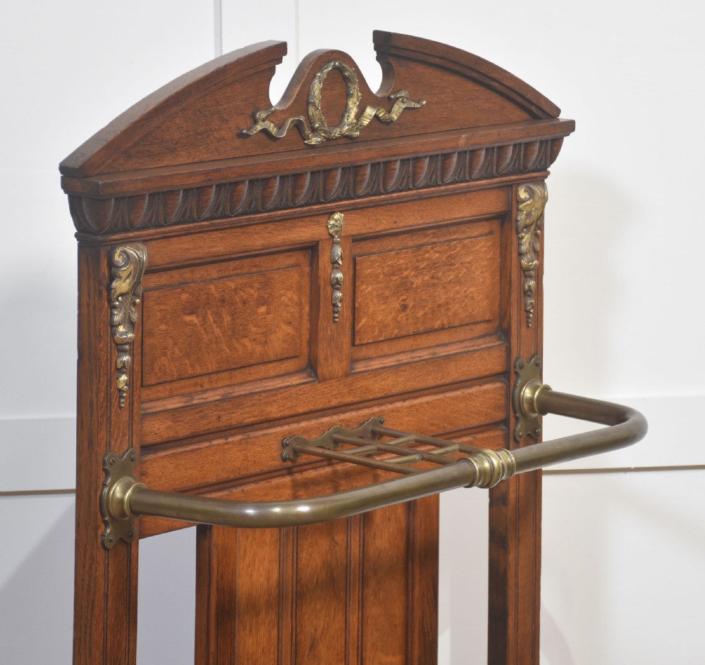An antique oak umbrella stand featuring an arched top pediment, brass retaining rail, decorative ceramic floral tiles, and a lower drip tray. View IX