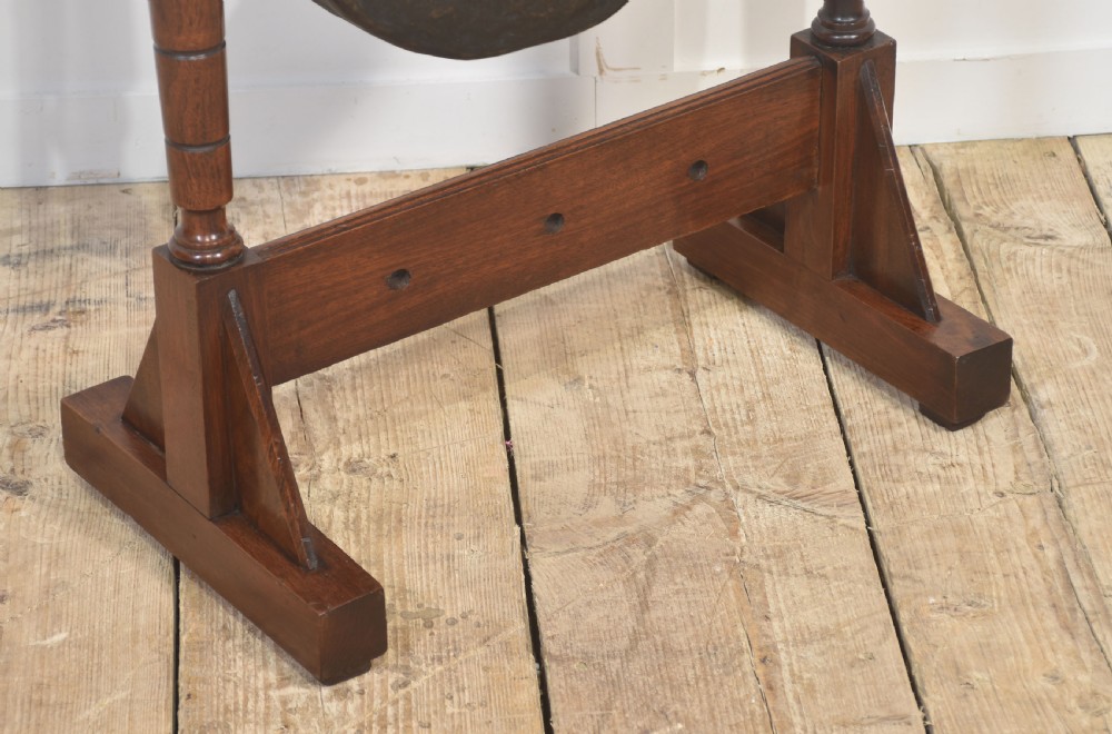 A freestanding dark mahogany frame with turned wooden pillars supporting a central circular brass gong disc and a suspended padded striker. View III