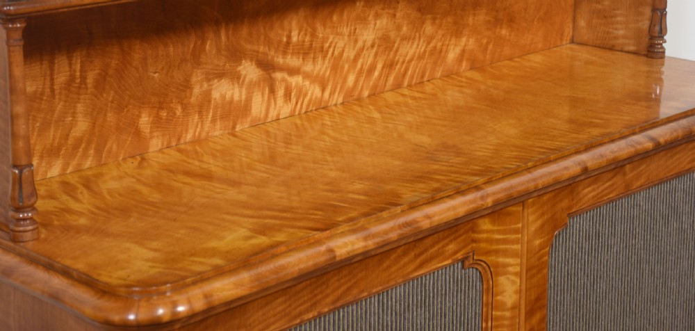 A William IV golden wood chiffonier featuring two open upper shelves with turned supports above a double-door cabinet with pleated fabric panels. View IX