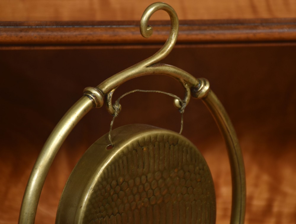 A brass tabletop dinner gong suspended within a circular frame set upon a wooden base, complete with a resting wooden striker. View II