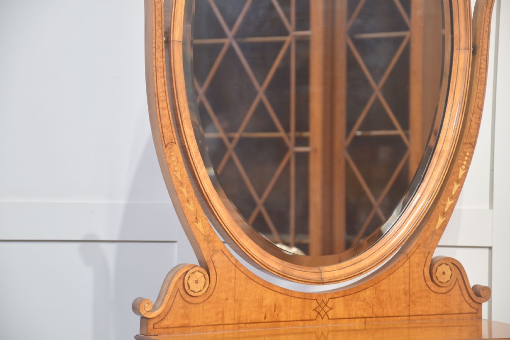 An oval satinwood dressing table mirror featuring marquetry inlay, curved supporting arms, and a two-drawer base resting on short turned feet. View VI