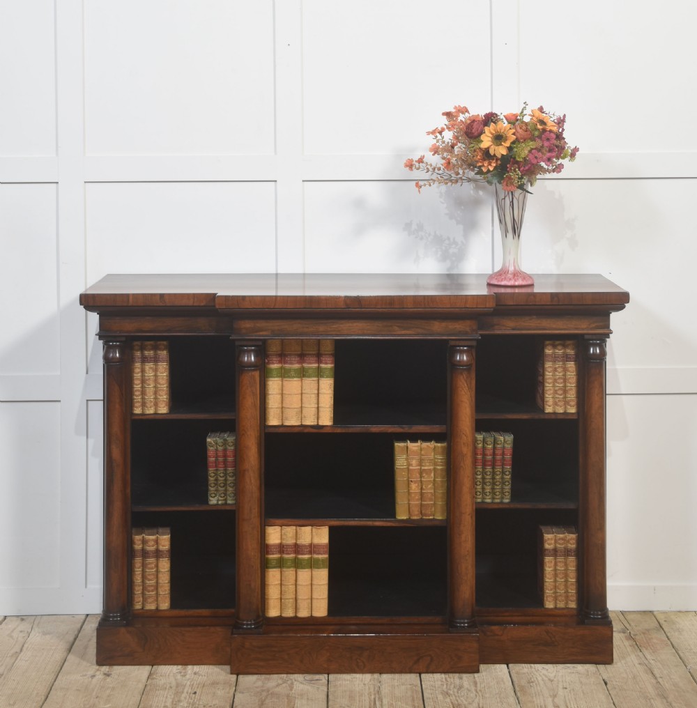 A nineteenth-century rosewood breakfront open bookcase with a projecting centre section flanked by turned column pilasters. View II