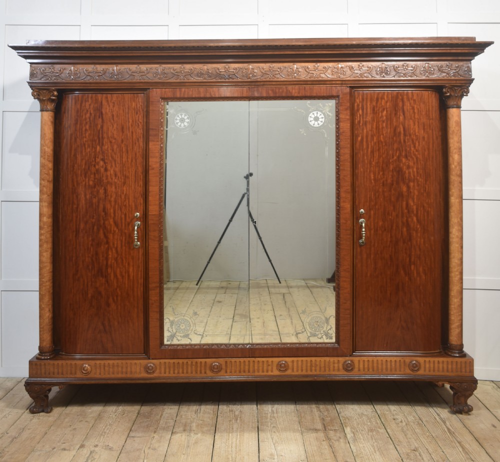 Large Victorian mahogany four-door wardrobe with central etched mirror doors, carved frieze, fluted side columns, and bracket feet.