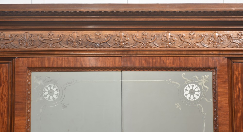 Large Victorian mahogany four-door wardrobe with central etched mirror doors, carved frieze, fluted side columns, and bracket feet. View V
