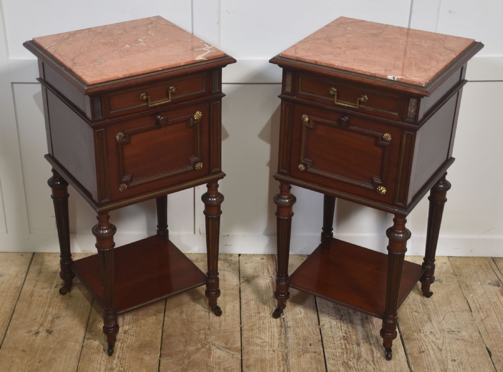 A matching pair of antique mahogany bedside cabinets with pink marble tops, single drawers, framed cupboard doors, lower shelves, and fluted legs on castors. View III