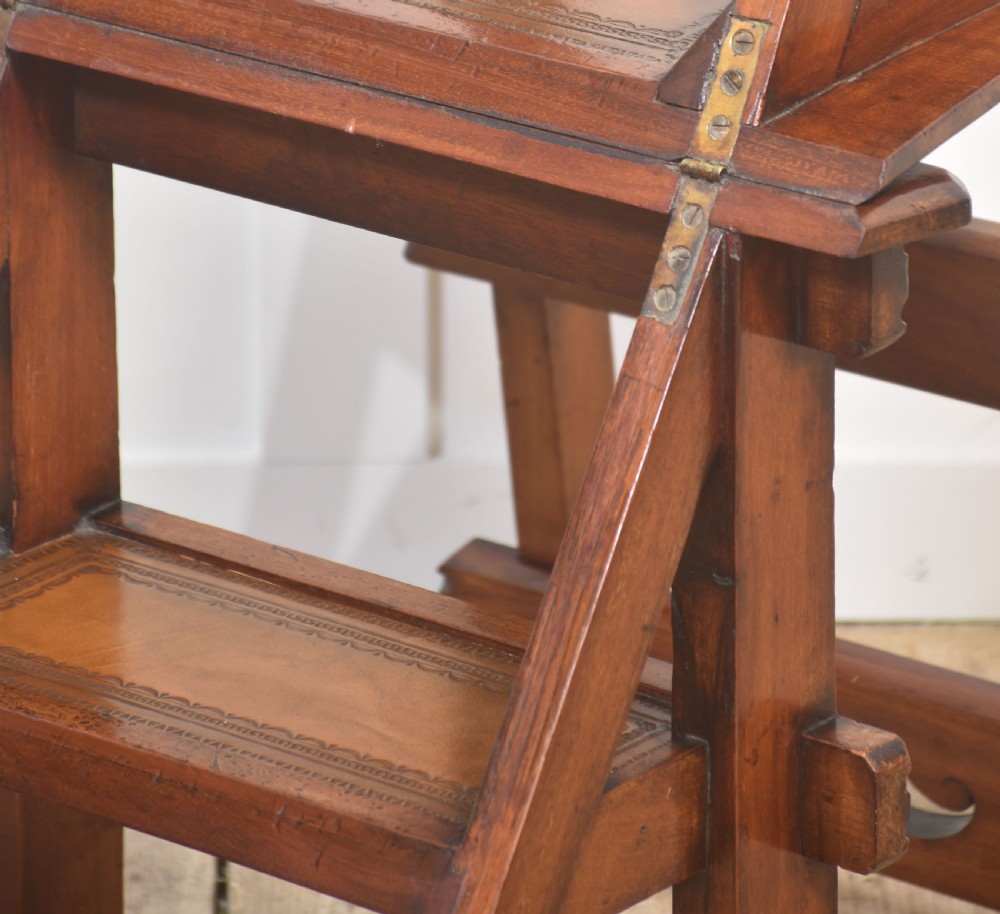 A warm brown walnut metamorphic library chair with carved trefoil backrest piercings and visible brass hinges. View X