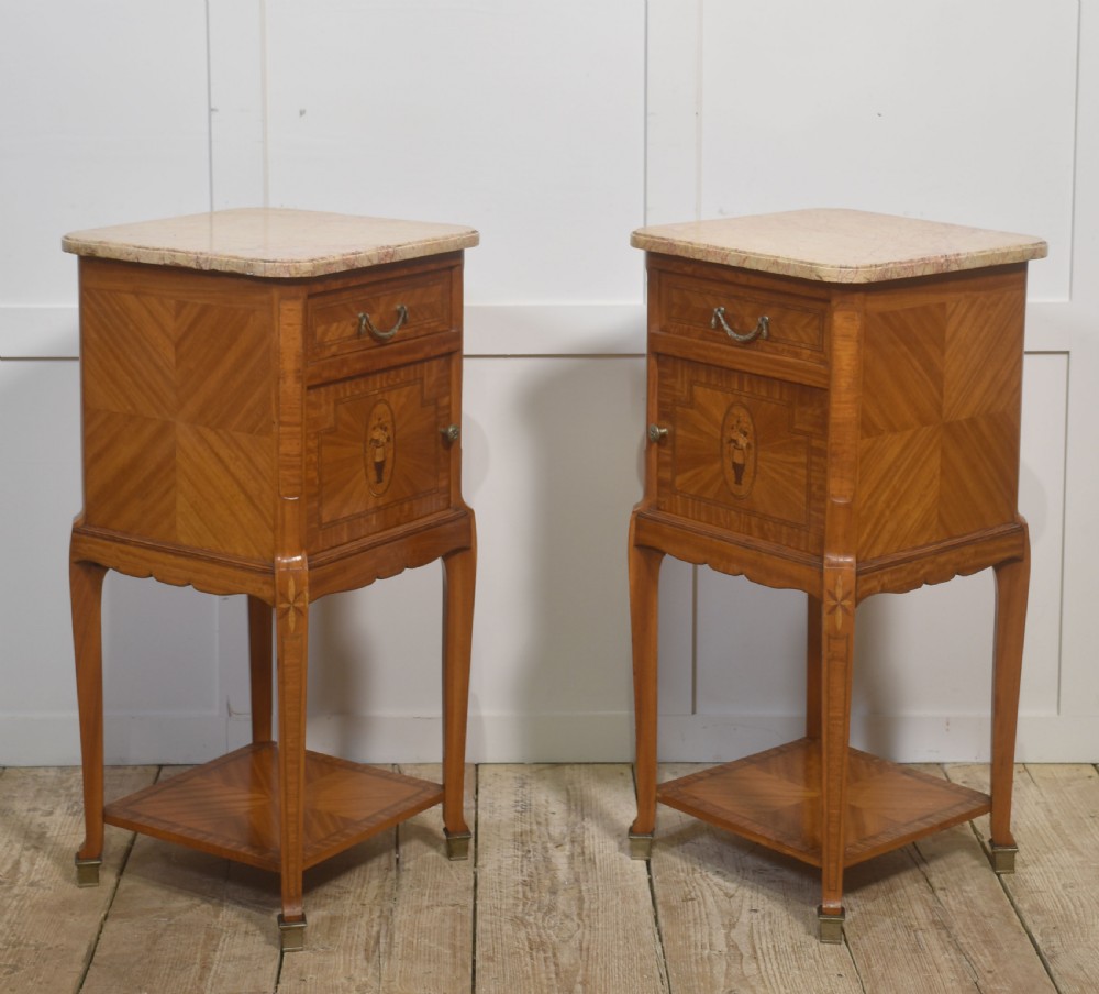 A pair of tall French satinwood bedside cabinets with marble tops, marquetry oval medallions, drawers, and slender legs. View V